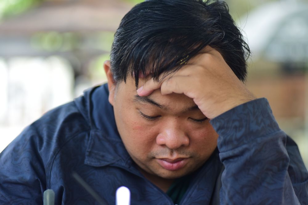 Pria termenung menopang kepala, merefleksikan keputusannya