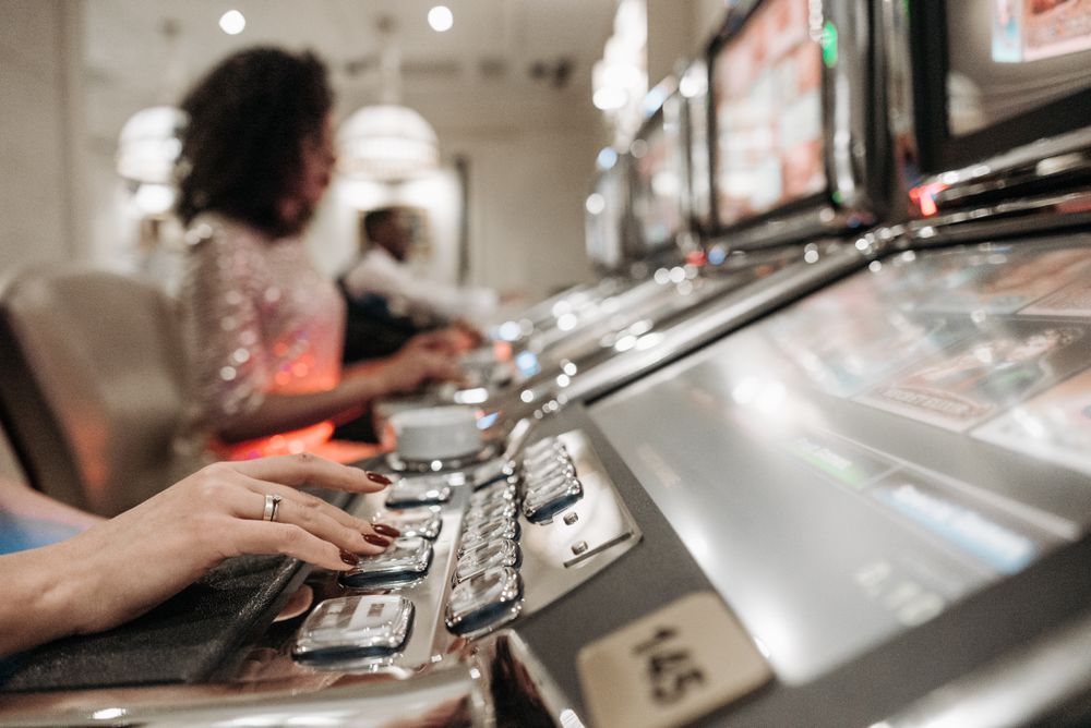 Tangan pemain bergerak di atas tombol mesin slot